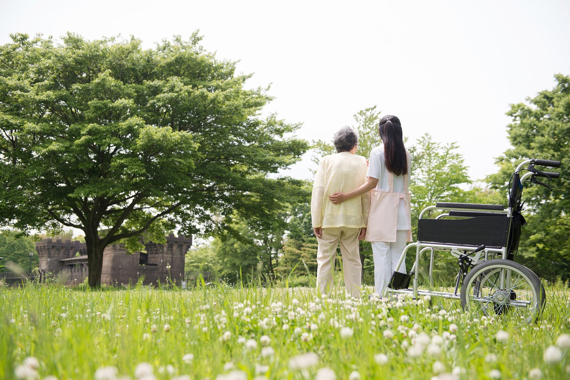 介護職員が入居者と屋外の緑地で散歩・余暇活動している風景